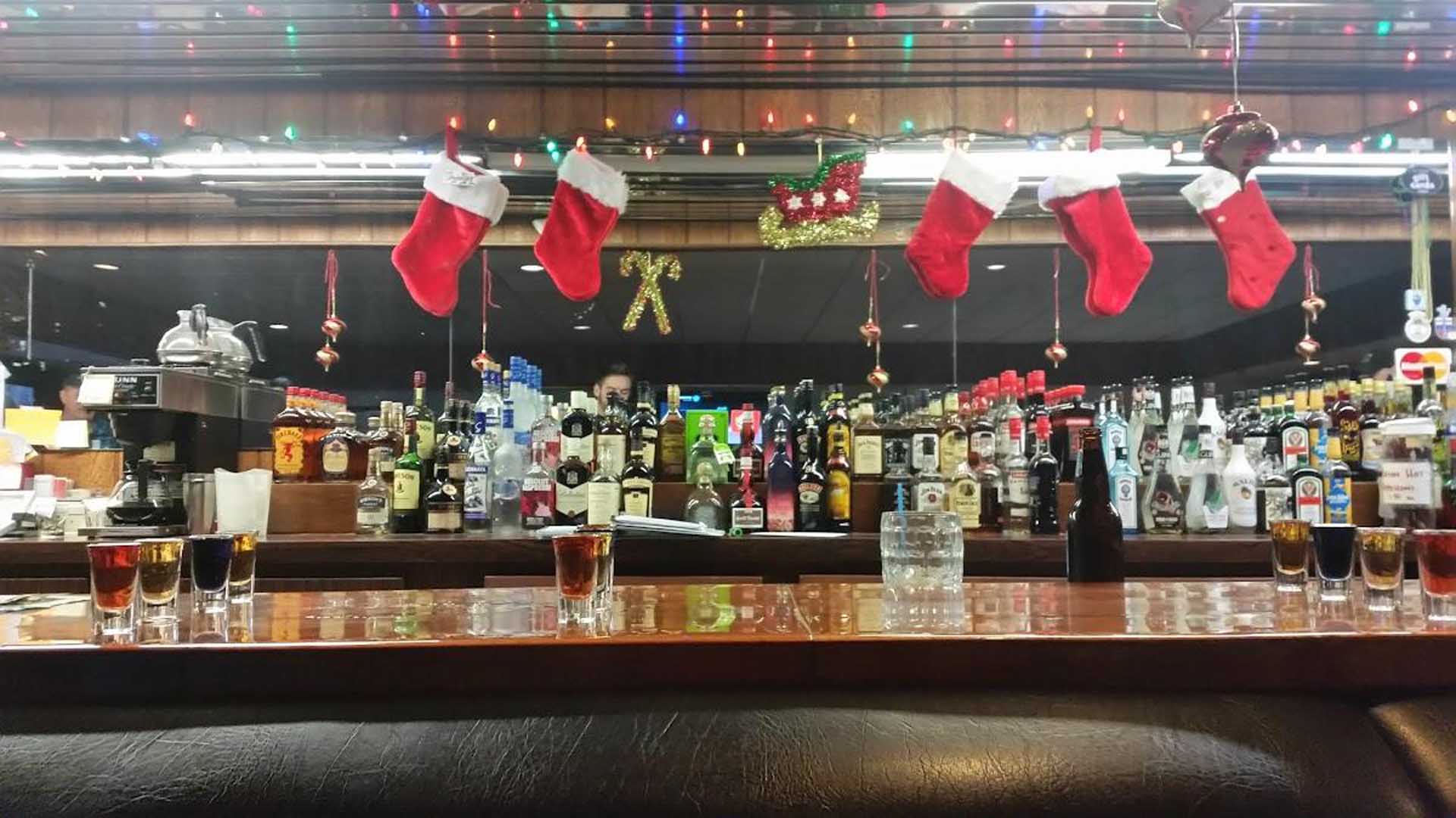 Christmas decor hung above a bar filled with alcohol bottles